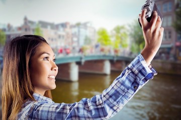 Composite image of smiling asian woman taking picture with