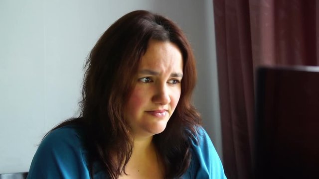 beautiful young emotional woman in front of computer watching awful thing with horrible scared face