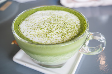 selective focus of hot green tea matcha latte in a cup on table