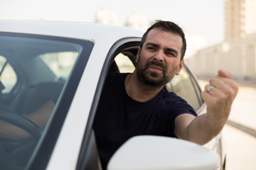 Angry driver pissed off by drivers in front of him and gesturing with hands. Road rage traffic jam concept.