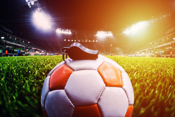 Football ball with whistle on the grass on soccer stadium, sunlight effect