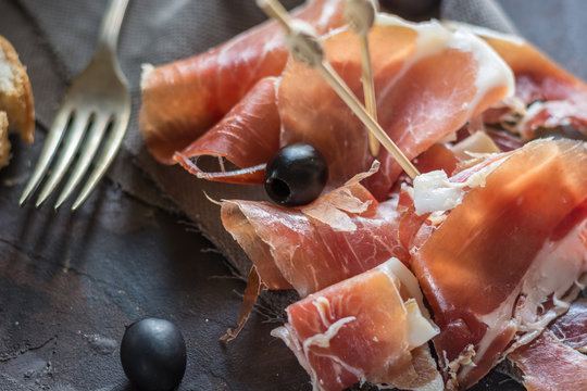 Portion of Ib&eacute;ric ham, along with bread and olives.