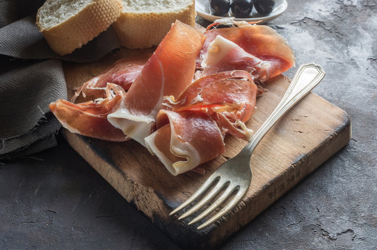Portion of Ib&eacute;ric ham, along with bread and olives.