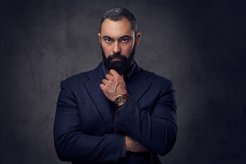 Serious, bearded male dressed in a suit.
