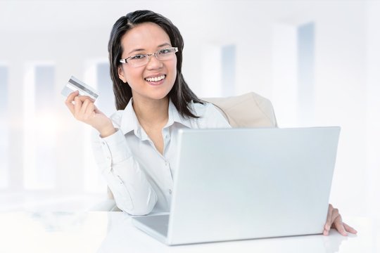 Composite image of smiling businesswoman holding credit card
