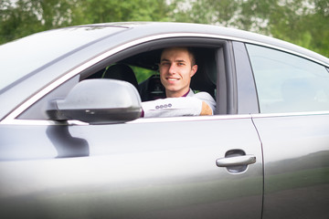 Young, happy, business man in the car. Man in a suits standing by the expensive, sport car. Successful young man. 