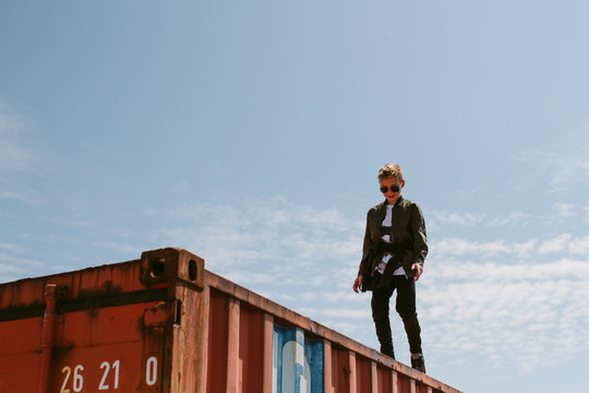 A teenage boy on the top of a shipping container