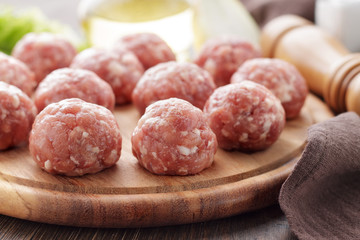 Raw meatballs from minced pork on cutting board.