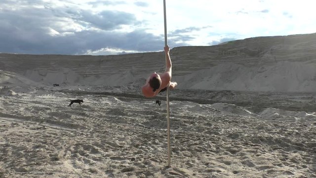 Man does tricks while dancing on a pole, he is studying.
