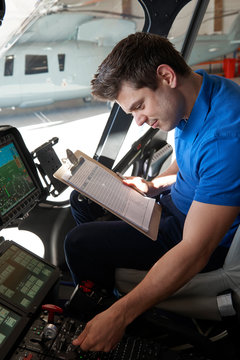 Male Aero Engineer With Clipboard Working In Helicopter Cockpit