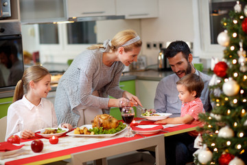Mother serving turkey to his family in Christmas dinner .