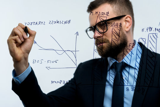 Man draws various growth charts, calculating prospects for success in a modern glass office
