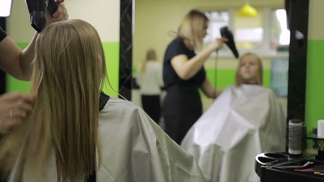 Female hairdresser drying hair with blow dryer