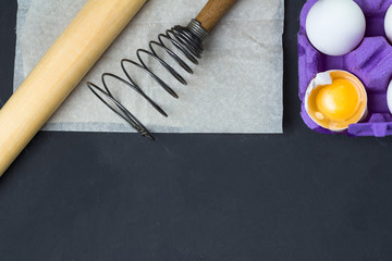 eggs in the tray, accessories for baking: whisk, rolling pin, paper.