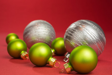 christmas baubles in green and silver on red background