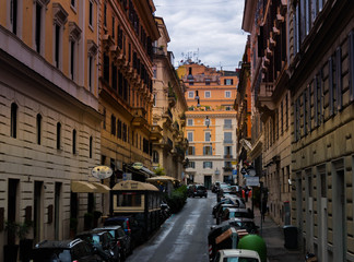  a colorful Roman street with dense carmakers and historic tenement houses