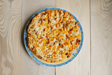 Homemade pumpkin pie on a plate on a wooden table. Top view.