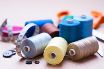 Pile of colorful spools of thread, buttons and measuring meter 