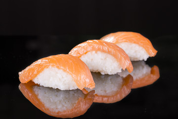 Sushi with salmon three pieces on a black background