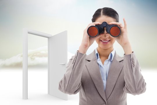 Composite image of businesswoman looking through binoculars