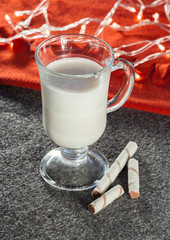 Christmas eggnog in the glass of mulled wine with cream and cinnamon and Christmas garland
