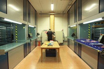 Male worker at automated vertical carousel storage unit in the warehouse  © Alex