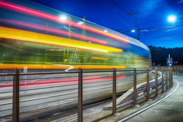 City tram speeding up in Tilikum Crossing at night, Portland, OR