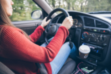 Happy young woman driving her car with coffee