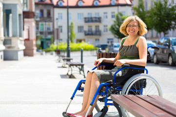 Naklejka na ściany i meble young adult woman on wheelchair on the street