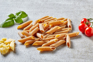 Penne pasta, cheese and vegetables on grey stone table