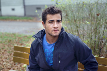 junger Mann, Teenager auf Parkbank, Herbst