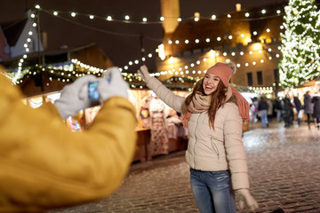 Obraz premium happy woman posing for smartphone at christmas
