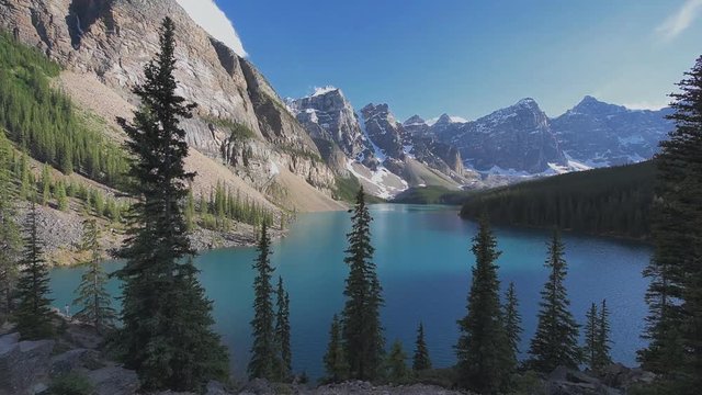 Beautiful sunset under turquoise waters of the Moraine lake with snow-covered peaks above it in Banff National Park of Canada.