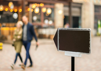 Empty arrow on a signpost. Couple walks on background
