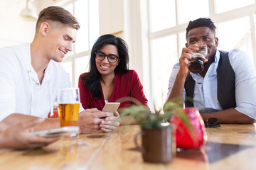 happy friends with smartphone drinking beer at bar