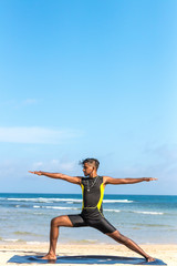 Fototapeta na wymiar Asian yoga man practice yoga on the beach with a clear blue sky background. Yogi on the tropical beach of Bali island, Indonesia.