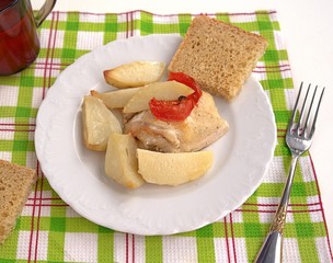Delicious dinner of chicken baked in sour-cream sauce with potatoes and tomatoes