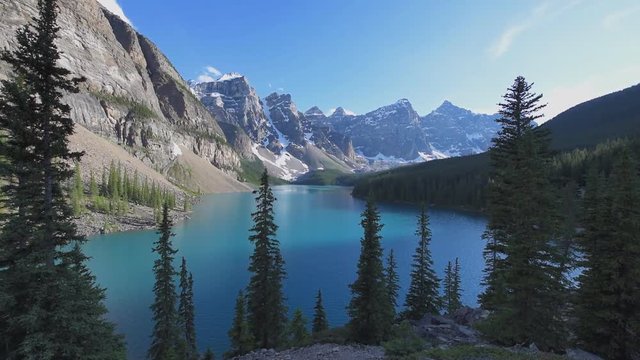 Beautiful sunset under turquoise waters of the Moraine lake with snow-covered peaks above it in Banff National Park of Canada.