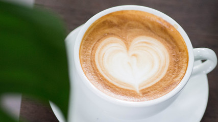 A cup of hot late in a green environment