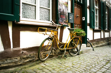 Fototapeta na wymiar Yellow Retro Bicycle In Old European Street Germany
