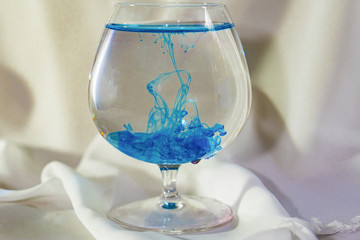 Blue or azure watercolor in a glass. Color mix in the glass. Oil paint in water.