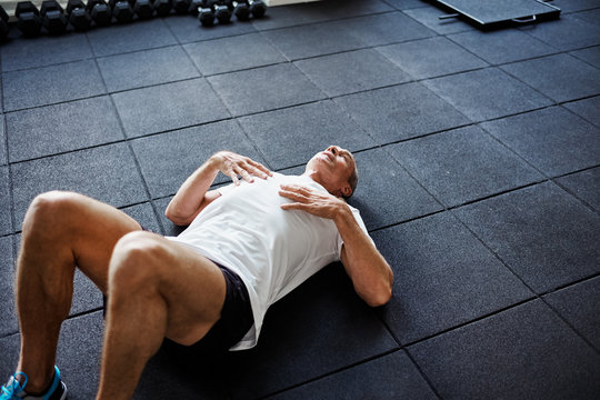 Exhausted man lying on a gym floor after working out