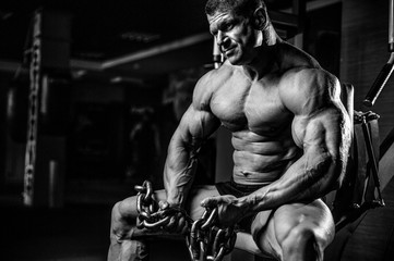 Fototapeta na wymiar Brutal bodybuilder working out in gym with chain.