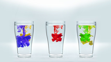 Glass of water with vibrant colors drop.
