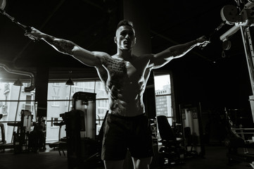 Fototapeta na wymiar Brutal Caucasian bodybuilder training chest in gym