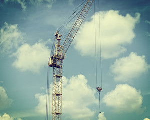 Vintage. Matte. Construction site. Big industrial tower crane with sky background. Old photo.
