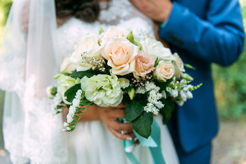 white with a green wedding bouquet in the hands of the bride and groom