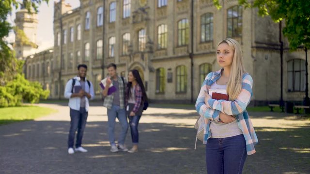 Group of multiracial fellows mocking humble newcomer girl at university