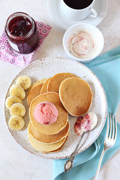 Banana pancakes with honey and caramelized bananas, fruit sorbet and cup of coffee, top view