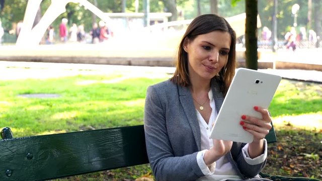 Businesswoman with tablet computer sitting on the bench in the city
